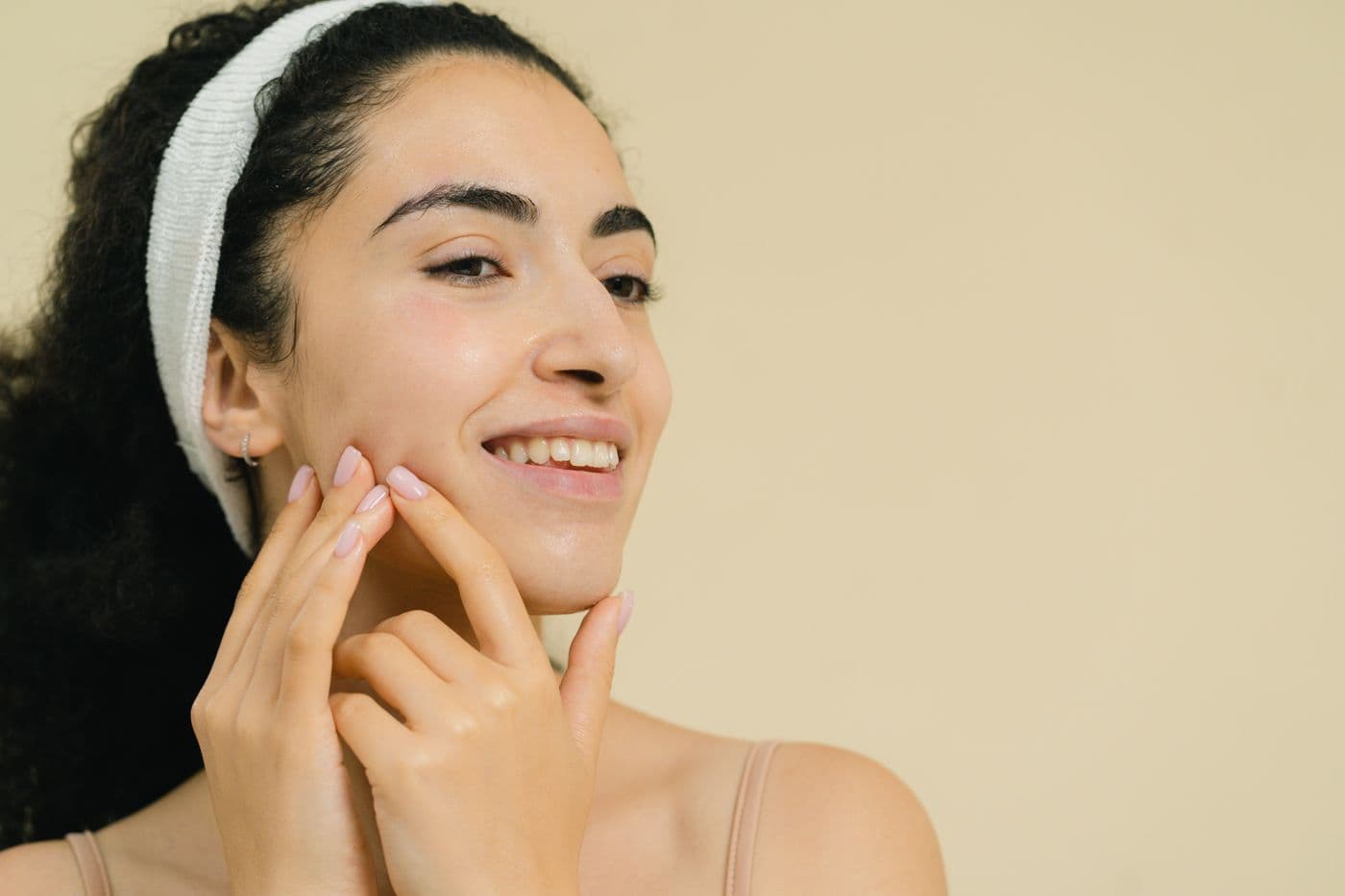Smiling patient in a spa headband touching her cheek